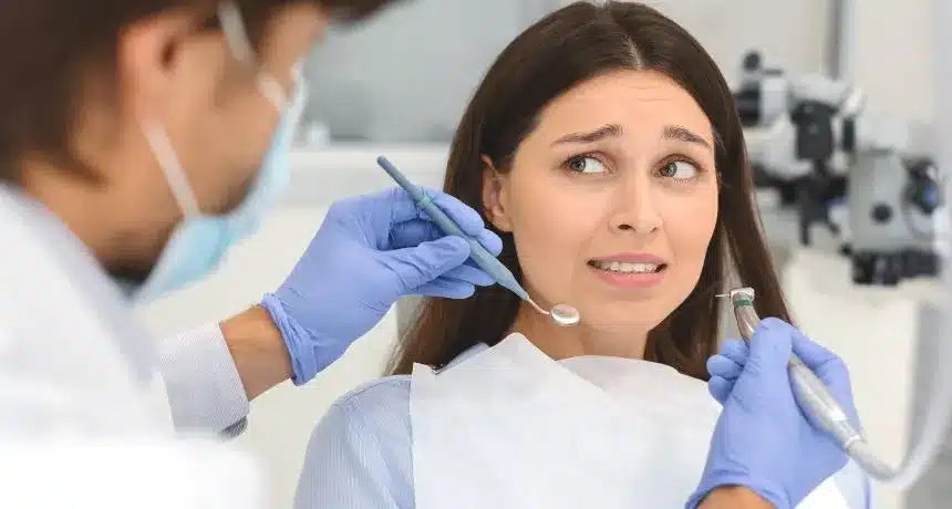 Anxious patient during dental exam while dentist prepares instruments for treatment