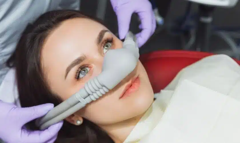 Female dental patient wearing a sedation mask while receiving comfortable dental treatment for sensitive teeth and anxiety.